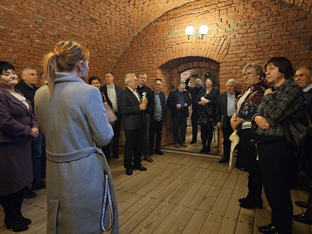 Osoby stoją w piwnicy pałacu w Walewicach. Na zdjęciu widać ponad 10 osób. 
